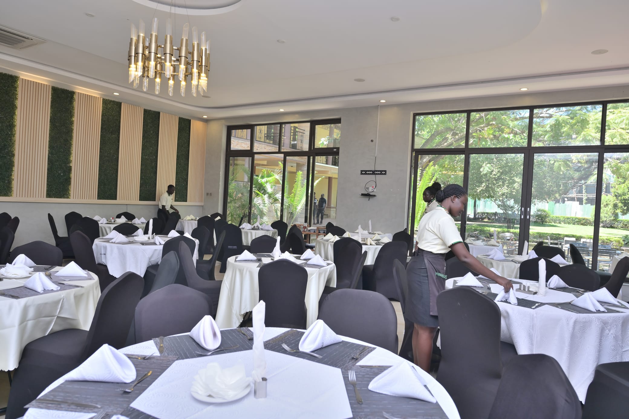 Staff setting round tables in the garden-view dining hall